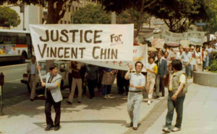 Foto de personas marchando bajo una pancarta que dice Justicia para Vincent Chin